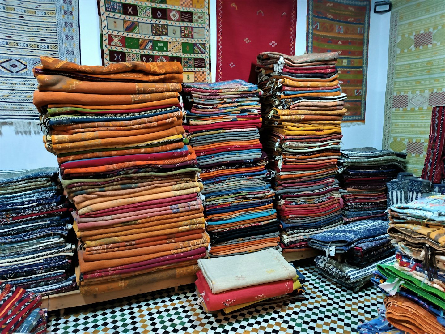Tappeti e tessuti colorati piegati impilati su piattaforme di legno.
